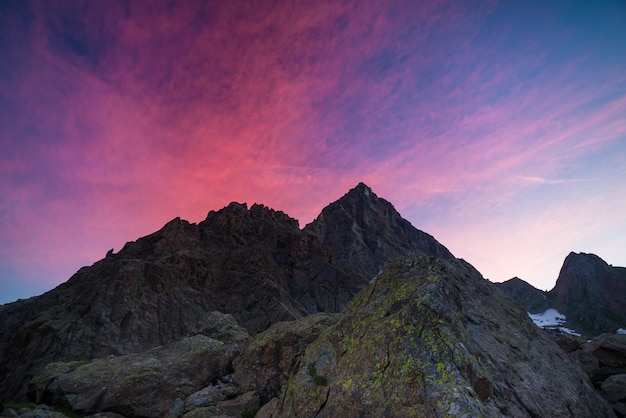 Bunter Himmel über felsiger Bergspitze auf den italienischen Alpen an der Dämmerung hinaus