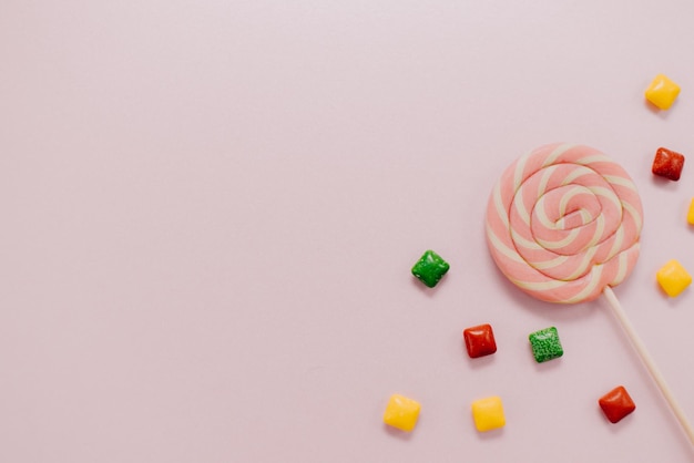 Foto bunter lutscher gestreifte spiralförmige mehrfarbige süßigkeit auf einer draufsicht des rosa hintergrundes