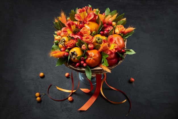 Bunter orange essbarer handgemachter Blumenstrauß steht in einem Vase auf einem Schwarzen