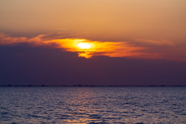 Bunter Sonnenaufgang auf See, Ölplattformen in der Ferne