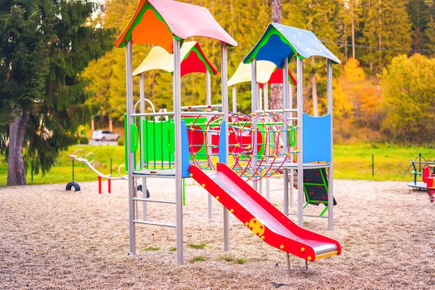 Bunter Spielplatz auf dem Hof im Park Bunte Kinderspielplätze im öffentlichen Park, umgeben von grünen Bäumen