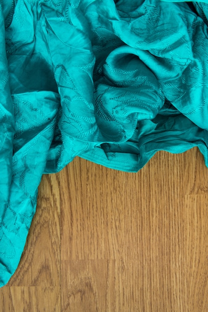 Bunter Textilabschluß oben in hellem Grün-Blau auf Holz