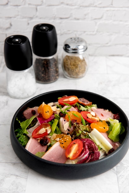 Bunter und frischer Salat mit Entenbrust, Rucola-Blättern, Orange, Granatapfelfrüchten und Blauschimmelkäse. Mit zerdrückten Walnüssen überzogen. Serviert in einer runden schwarzen Steinplatte auf einem dunklen Marmorbrett.