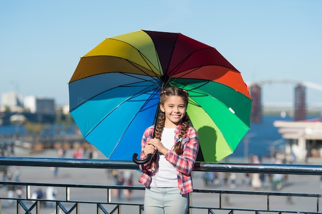 Buntes Accessoire für fröhliche Stimmung Sie mag helle Accessoires Regenschirm für Kinder Versteckt vor Problemen Positiv und hell Mädchen niedliches Kind, das mit buntem Regenschirm steht Kind unter Regenschirm