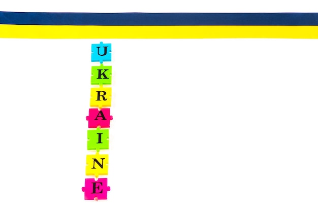 Buntes blaugelbes Stoffband und Puzzles aus Buchstaben Ukraine, isoliert auf weiss Das Symbol des Staates