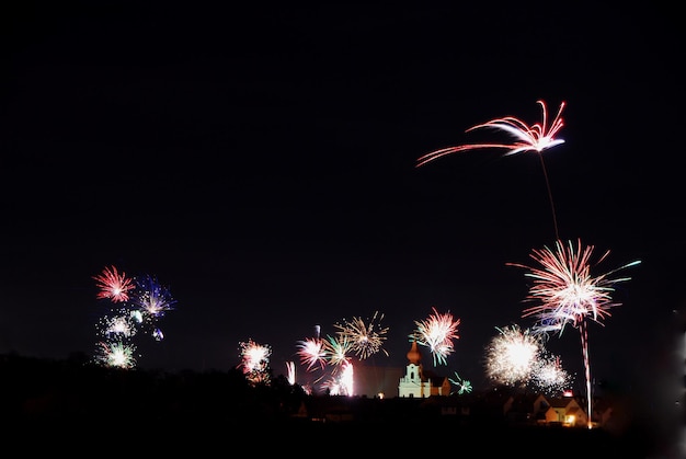 Buntes grosses feuerwerk bei einer kirche in der nacht zu silvester mitternacht