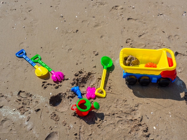 Buntes Kinderstrandspielzeug auf Sandhintergrund