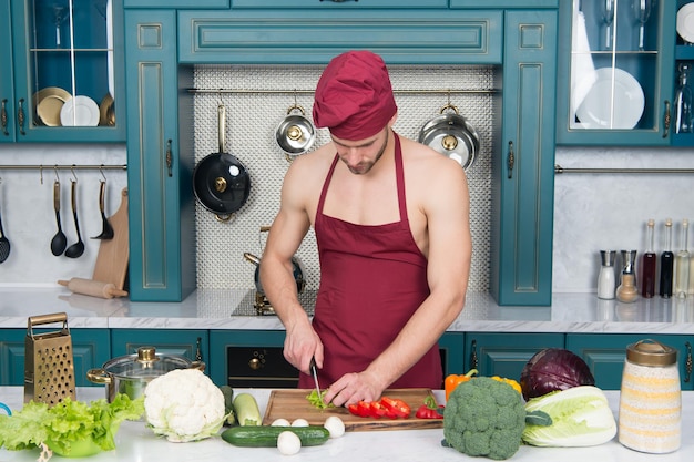 Buntes kulinarisches für Diätküche mit Leidenschaft muskulöser Mann kocht Essen Wunsch nach Geschmack Koch in der gewerblichen Küche Vitaminsalat Mann kocht leckeres Essen Gesunde Ernährung und Leben Koch hält Messer