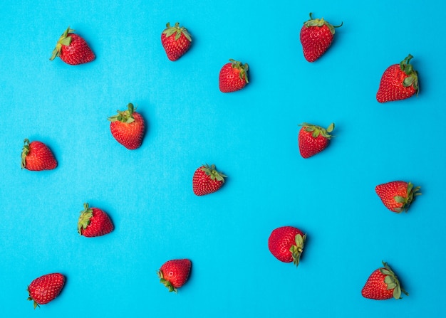 Buntes Muster aus Erdbeeren auf hellblauer Oberfläche.