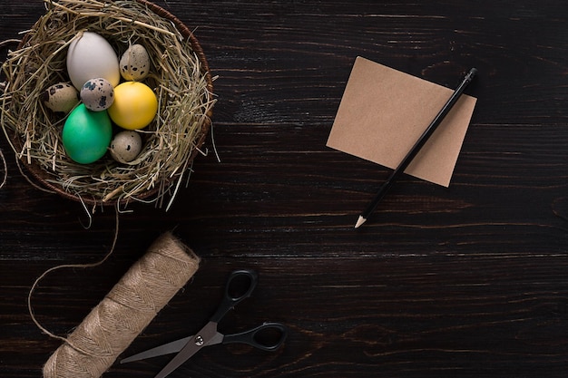 Buntes Osterei im Nest auf dunklem Holzbrett