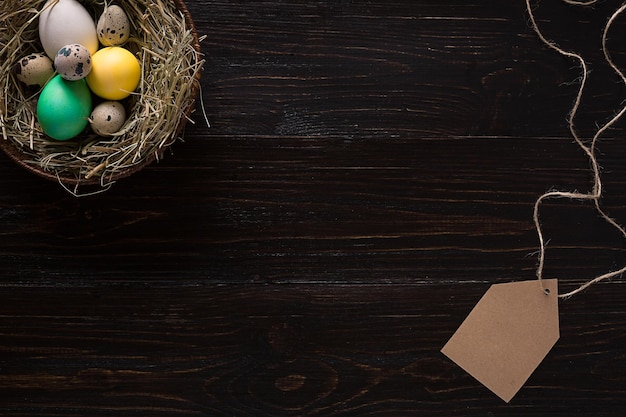 Buntes Osterei im Nest auf dunklem Holzbrett