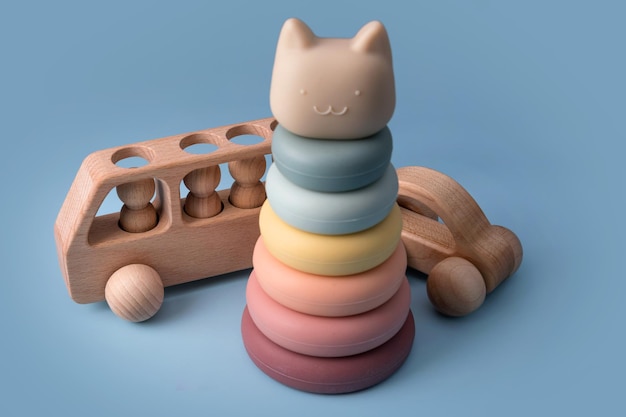 Buntes pädagogisches Montessori-Kinderspielzeug auf blauem Hintergrund. Sinnesbälle für Kinder, Holzautos und Silikonpyramide, Multiball-Set aus strukturiertem Kunststoff für Babys und Kleinkinder, Turmspielzeug.
