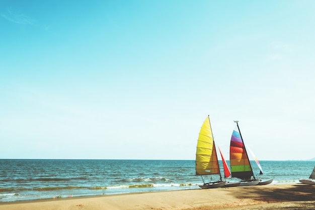 Buntes Segelboot auf tropischem Strand am Sommer.