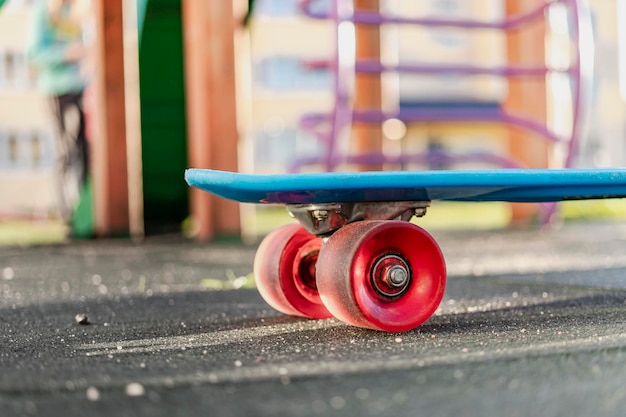 Buntes Skateboard mit orangefarbenen Rädern in der Nähe auf dem Spielplatz