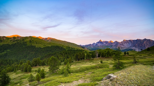 Buntes Sonnenlicht auf den majestätischen Berggipfeln, dem Waldland und den Tälern der italienischen französischen Alpen