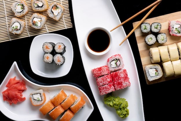 Buntes Sushi mit Wasabi, Ingwer, Sauce und Stäbchen