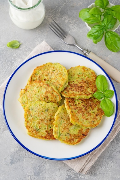 Buñuelos de calabacín con queso, ajo y hierbas Tortitas de calabacín servidas con albahaca y crema agria