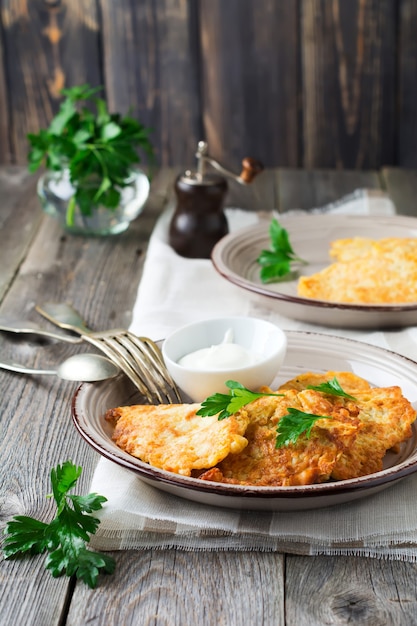 Buñuelos de calabacín, tortitas caseras de calabacín vegetariano con hierbas frescas y salsa de yogur en un plato de cerámica blanca sobre la mesa de madera vieja. Estilo rústico. Enfoque selectivo Vista superior. Lugar para el texto.