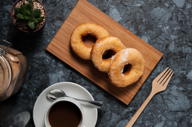 Buñuelos deliciosos con la formación de hielo y la taza de café en placa en la tabla de mármol negra.