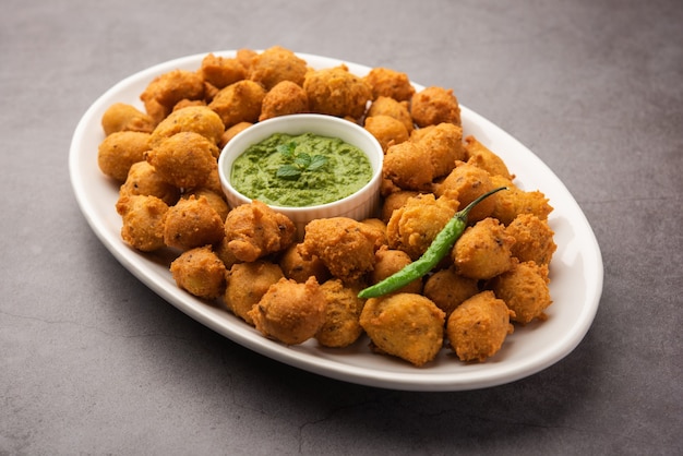 Buñuelos especiales de monzón Moong Dal Vada, Pakoda, Dalwada, Pakora o Mungdal Bhajiya o buñuelos amarillos servidos con salsa picante verde