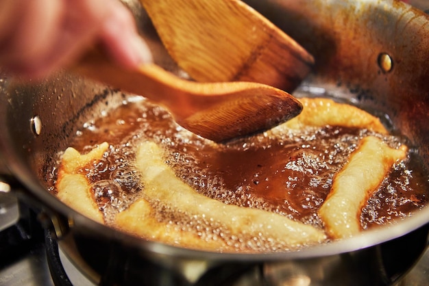 Buñuelos franceses Bugnes en aceite hirviendo en una cacerola