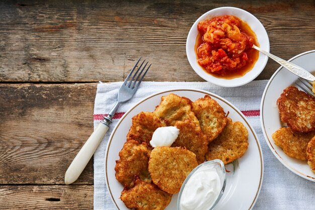 Buñuelos de patata con crema agria y salsa de tomate en mesa de madera