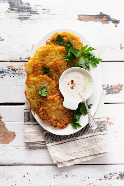 Buñuelos de patata Draniki, tortitas de patata vegetarianas, servidas con hierbas frescas y salsa de yogur de ajo