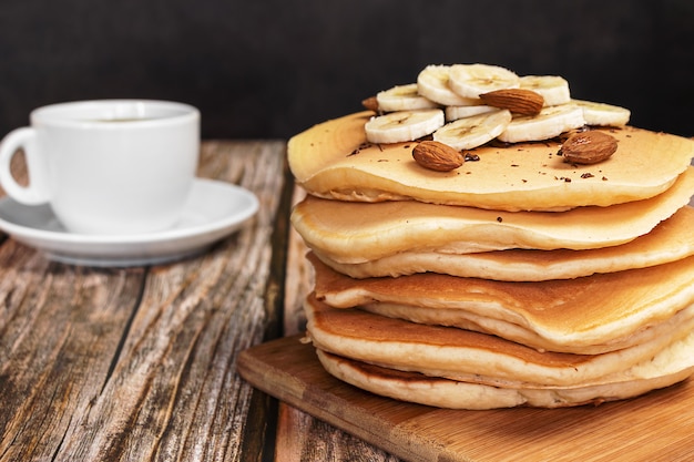 Buñuelos en una tabla de madera con una taza de café sobre una pared oscura en un primer plano