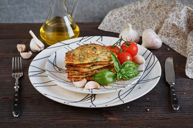 Buñuelos vegetarianos de calabacín servidos con hierbas frescas tomates y ajo Enfoque selectivo