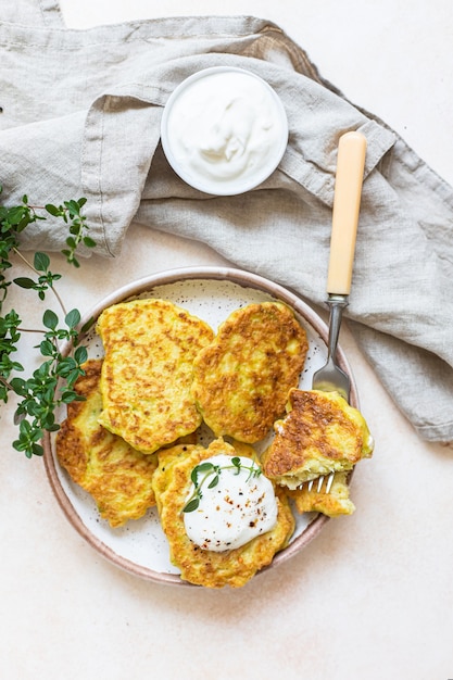 Buñuelos de verduras o tortitas con yogur o aderezo de crema agria y hierbas. Buñuelos de repollo o calabacín en plato de cerámica. Comida vegetariana saludable. Enfoque selectivo. Vista superior.