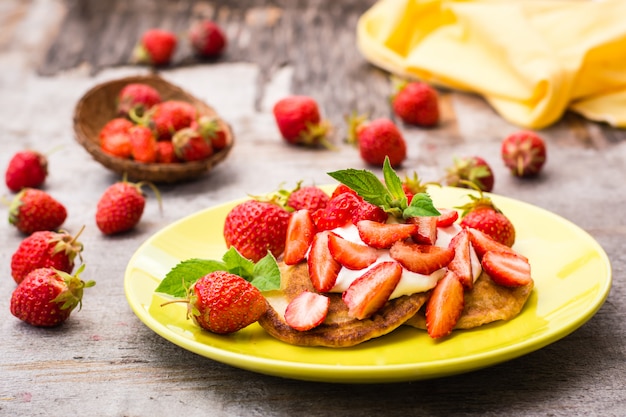 Buñuelos con yogurt, rodajas de fresas y hojas de menta en un plato