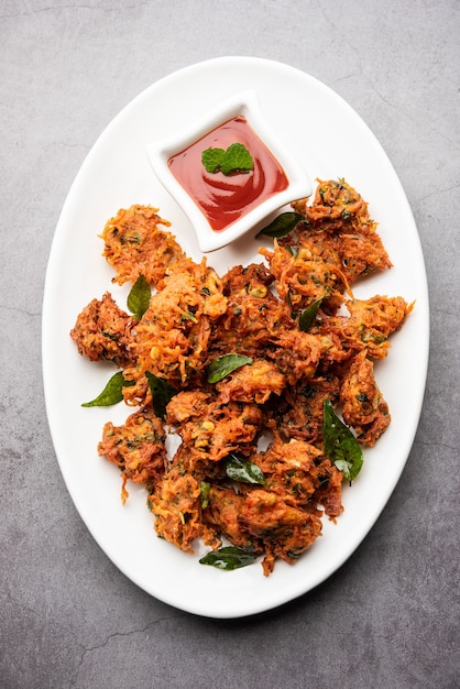 Buñuelos de zanahoria o Gajar ke pakore o pakode o bajji o bhaji, bocadillo indio servido en un plato con salsa de tomate