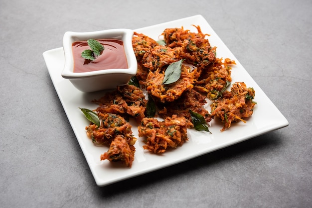 Buñuelos de zanahoria o Gajar ke pakore o pakode o bajji o bhaji, bocadillo indio servido en un plato con salsa de tomate