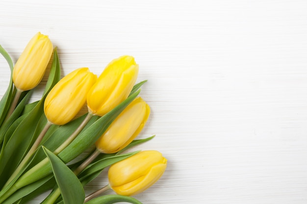 Buquê amarelo de tulipas em fundo branco de madeira. Cartaz da primavera com espaço de texto livre.