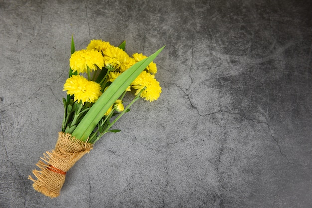 Buquê amarelo mãe flores primavera e pandan embrulhado em saco no fundo do prato escuro