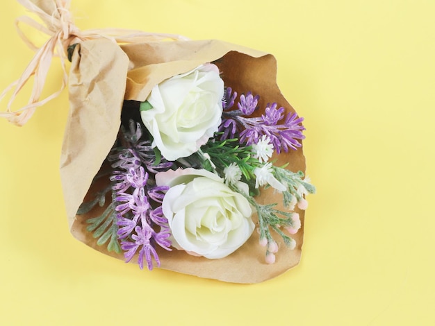 Buquê artificial de flores da primavera em papel ofício em um fundo amarelo