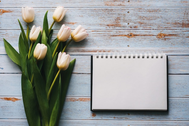 Buquê branco de tulipas em uma mesa de madeira com notebook