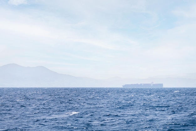 buque de carga navegando entre la niebla marina cerca de la costa en un día soleado concepto de transporte marítimo de mercancías y espacio de copia de comercio de importación y exportación para texto