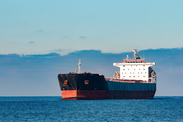 Foto buque de carga negro moviéndose en agua del mar báltico. riga, europa