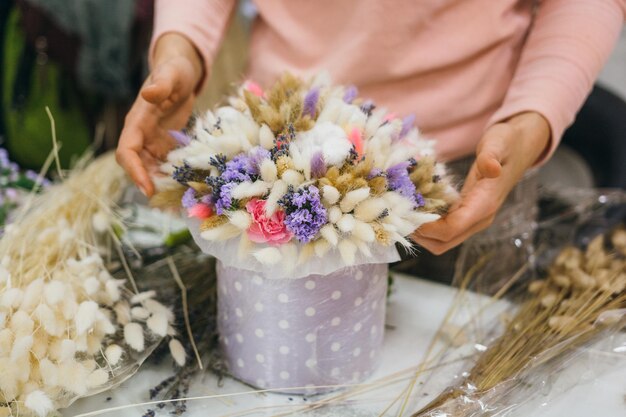 Buquê colorido de diferentes flores frescas nas mãos de uma florista Fundo de flores rústicas