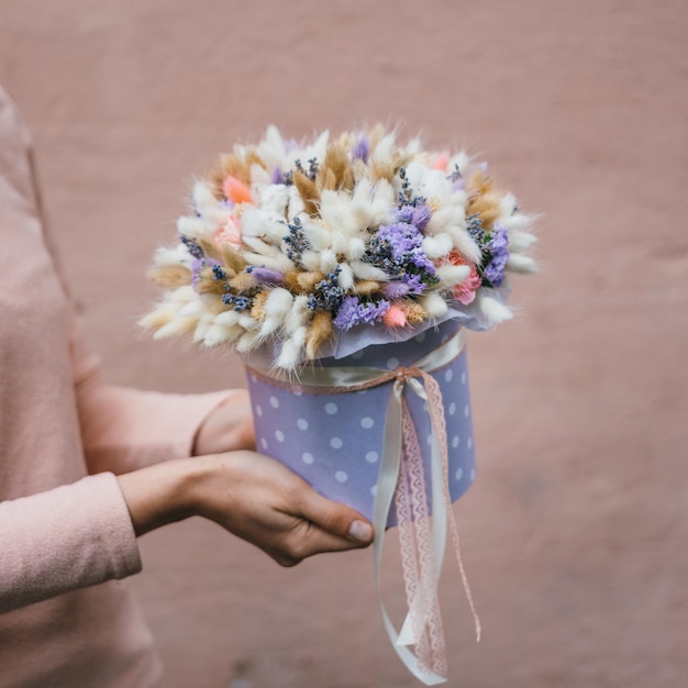 Buquê colorido de diferentes flores secas de madeira morta nas mãos de uma florista