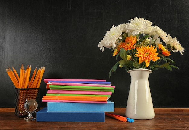 Buquê de cadernos de flores e livros na mesa de madeira