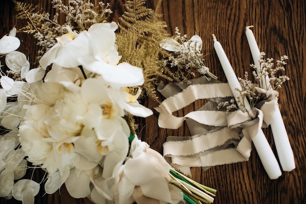 Buquê de casamento branco e velas em uma mesa de madeira