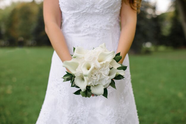 Buquê de casamento branco lindo delicado de Calla e hortênsia com vegetação nas mãos da noiva