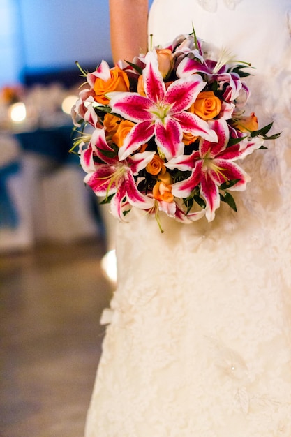 Buquê de casamento com lírios cor de rosa e rosas laranja.
