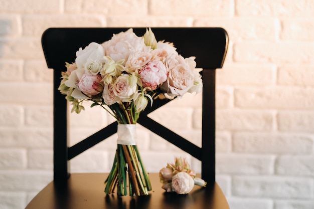 Buquê de casamento com peônias e rosas em uma cadeira e flor na lapela. a decoração no casamento.