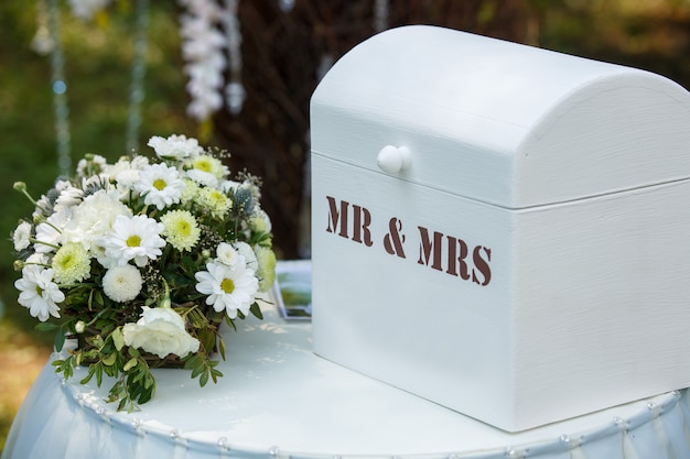 Buquê de casamento e decoração perto de caixa com inscrição sr. e sra.
