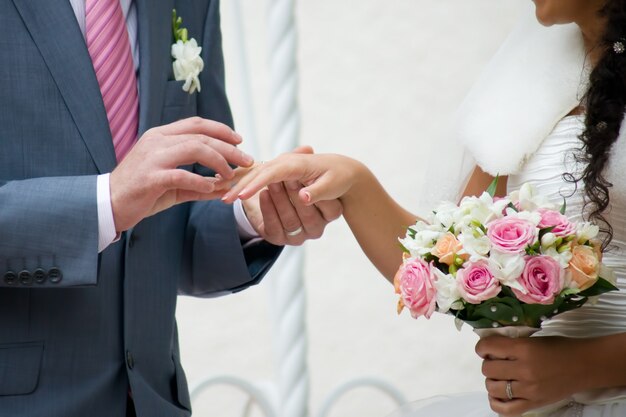 Buquê de casamento e mãos com anéis