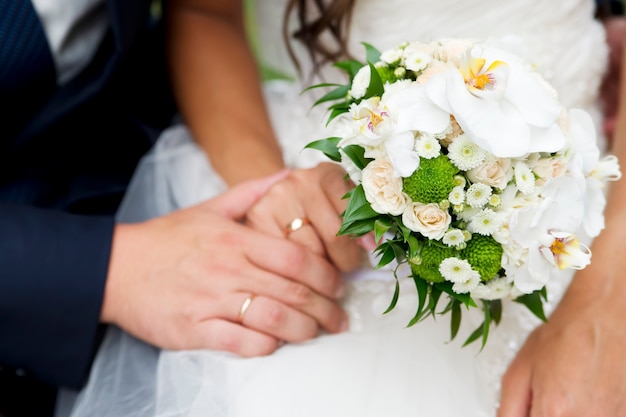 Buquê de casamento e mãos com anéis