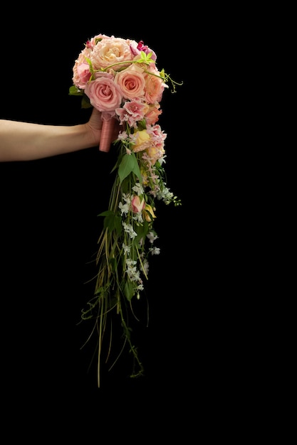 Buquê de casamento em cascata exclusivo na mão de uma mulher em um fundo preto